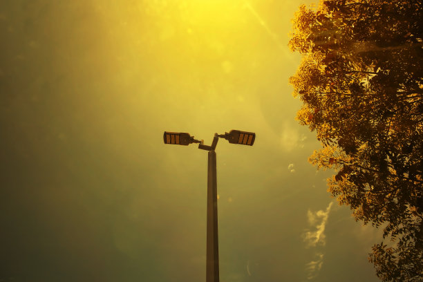 日落时分，橘黄色的天空上出现了几棵树。天空中有一盏led太阳能灯。图片下载