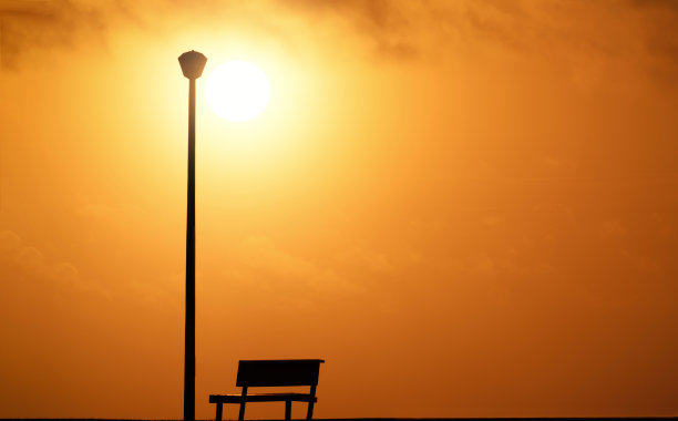 木凳和街灯，背景是夕阳和灿烂的太阳。图片下载