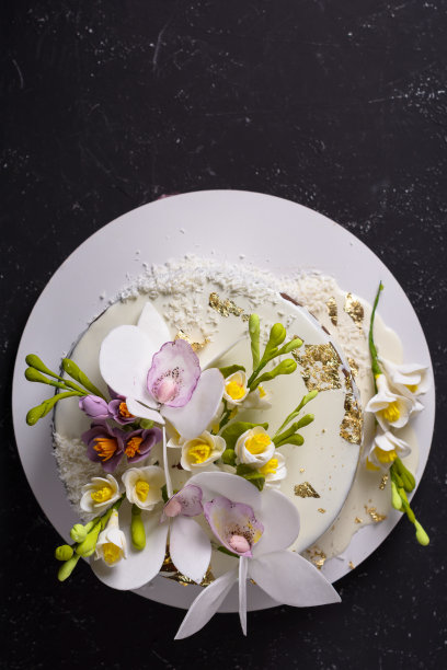 巧克力蛋糕装饰鲜花和倒白色糖霜在黑色的石头背景。前视图。平的。图片下载