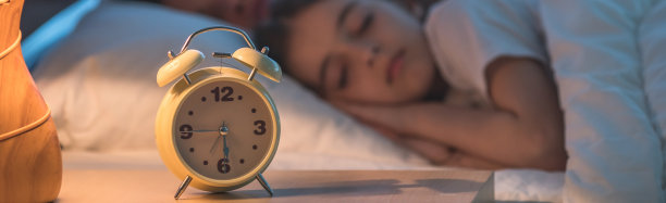 在熟睡的家庭背景上的闹钟。晚上的时间图片下载