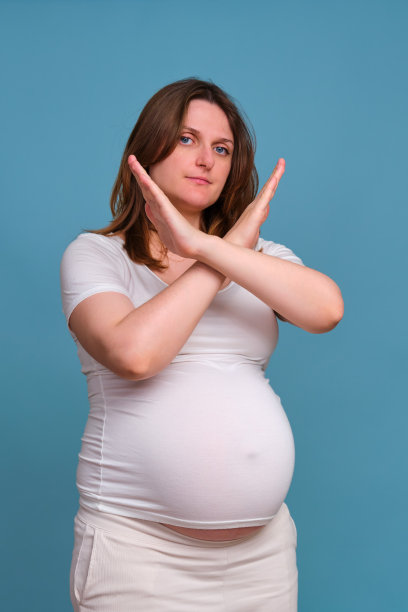 一幅在蓝色背景上做着拒绝手势的孕妇肖像图片下载