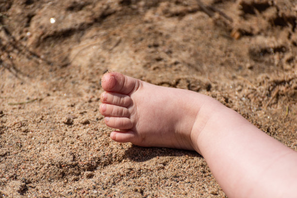 一个婴儿的脚在沙子里。图片下载