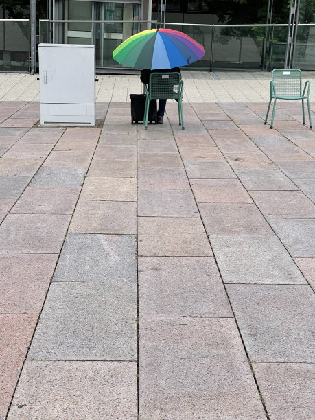 彩虹伞藏着一个坐在镇广场上的人图片下载