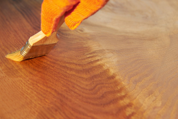 在橡木板上用清漆涂漆，手套和刷子。图片下载