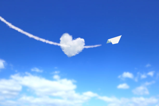 纸飞机穿过一个心形的云。图片下载