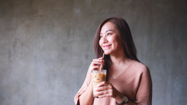 一个漂亮的年轻女子拿着冰咖啡喝图片下载