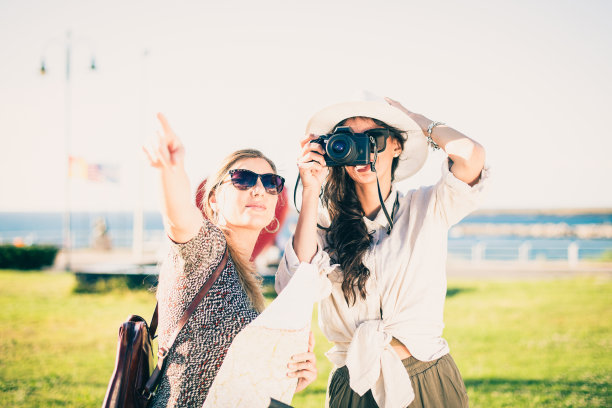 两个快乐的年轻游客背着背包，带着旅游地图和相机。图片下载