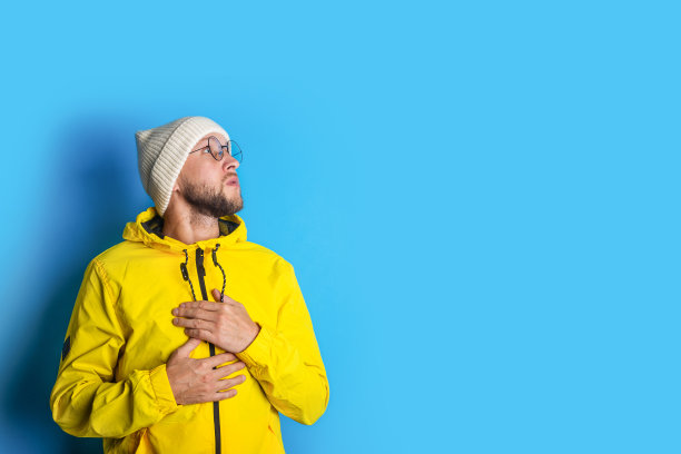 一个留着胡子的年轻人双手撑着胸膛，仰望着蓝色的背景图片下载