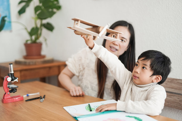 亚洲保姆和孩子有好玩的时间与木头飞机在家里图片下载