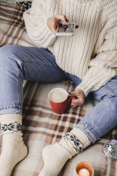 女性手用智能手机为社交网络拍摄新年或圣诞节的平面照片。为假期做准备，创造内容。可可杯加棉花糖图片下载