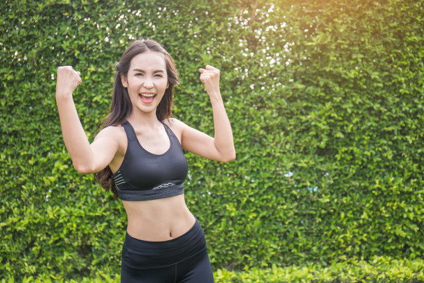 运动的年轻亚洲女人显示二头肌。亚洲妇女伸展她的身体在户外图片下载