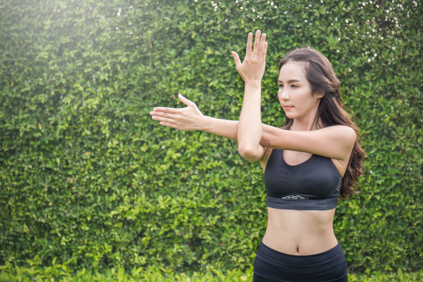 运动的年轻亚洲女人显示二头肌。亚洲妇女伸展她的身体在户外。图片下载