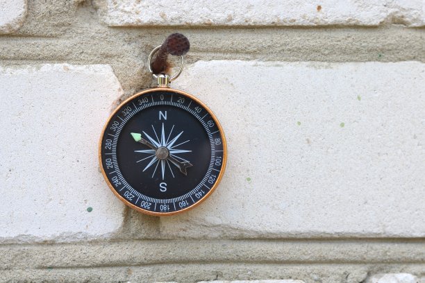 经典的导航指南针以砖墙为背景，象征旅游用指南针，旅游用指南针，户外活动用指南针图片下载
