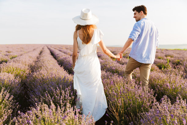 美丽的年轻夫妇的照片，男人和女人笑着，走在薰衣草田的户外图片下载