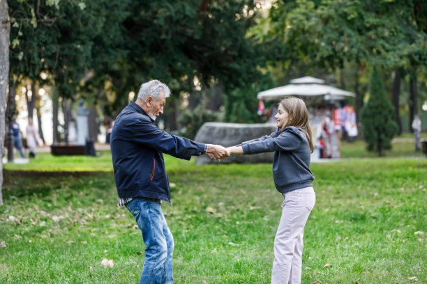 小女孩和她的爷爷正在公园里度过一个秋日。图片下载