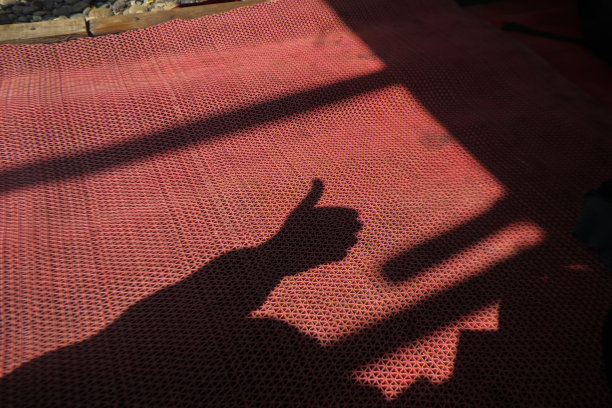 在红色塑料地毯上竖起大拇指象征影子图片下载