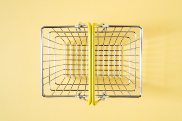 空的购物篮，黄色的提手，米色的背景。前视图。图片下载