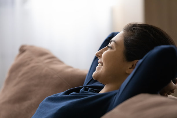 近距离的微笑梦幻般的印度女人在沙发上休息图片下载