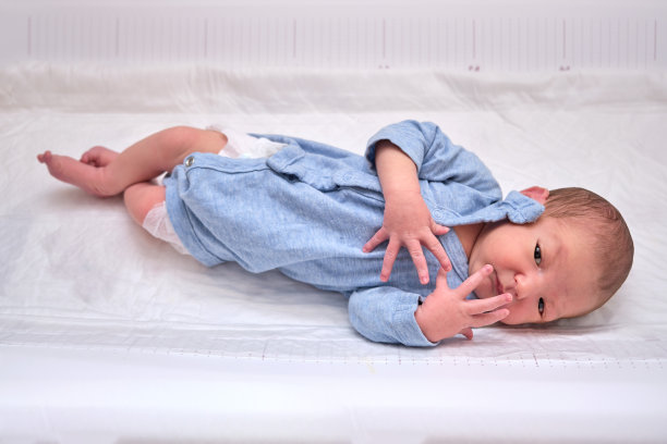 一个穿着蓝色衣服的新生婴儿躺在换衣服的桌子上，有摩洛反射图片下载