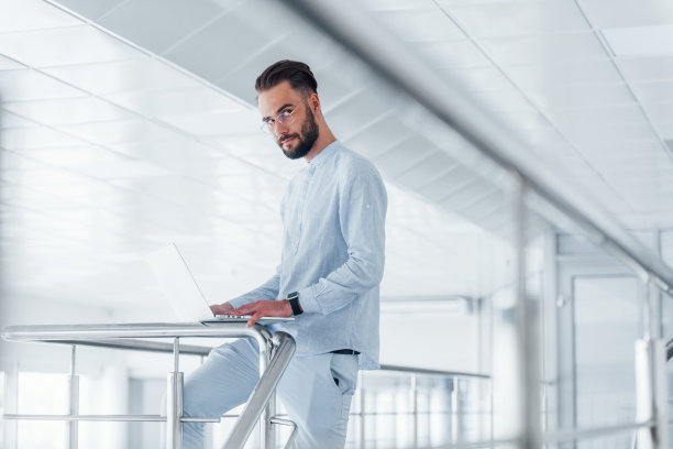 使用笔记本电脑。年轻英俊的男人白天在办公室里穿着正式的衣服图片下载