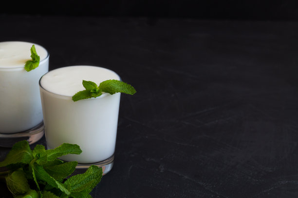 白色的拉斯饮料与新鲜的绿色薄荷在黑色的背景。寒冷的乳制品。印度菜。副本的空间。艾兰，深色桌子上的益生菌酸奶。健康、发酵产品理念。图片下载