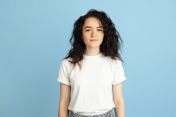 年轻美丽的卷发白人妇女的肖像孤立在浅蓝色工作室背景。图片下载