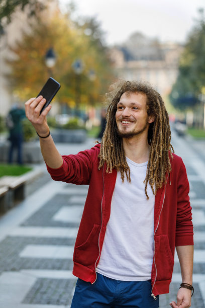 快乐的年轻人在街上自拍。图片下载