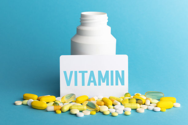 在卡片上写上维生素。瓶子里有蓝色背景的彩色药丸。医学概念。特写镜头。图片下载