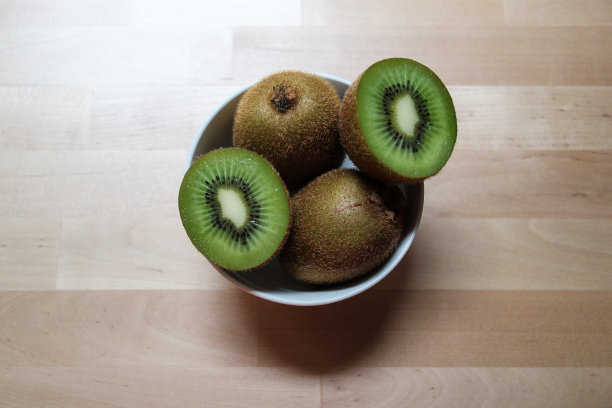 健康的猕猴桃放在一个白色的碗里，成熟的整个猕猴桃和一半猕猴桃，有选择的重点图片下载