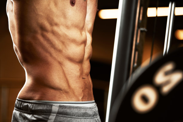 一个肌肉发达的男人在健身房练杠铃的特写。残忍的健美运动员运动员有六块腹肌，完美的腹肌，肩膀，二头肌，三头肌和胸部图片下载