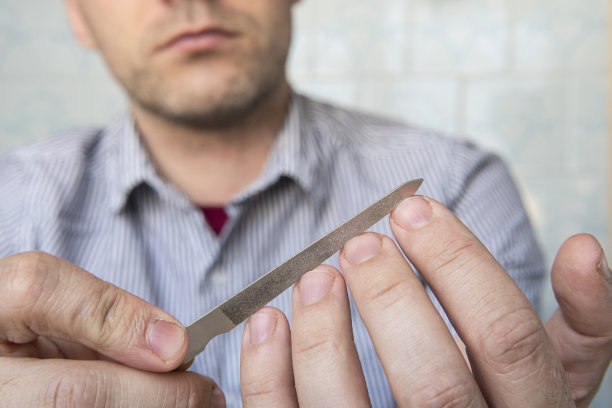 一名男子用指甲锉修剪他手上的指甲。特写镜头。有选择性的重点。图片下载