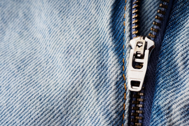 一个金属拉链和一条狗在牛仔裤上的特写。牛仔服装的元素。用于缝纫的牛仔背景。天然、耐用的牛仔布面料图片下载