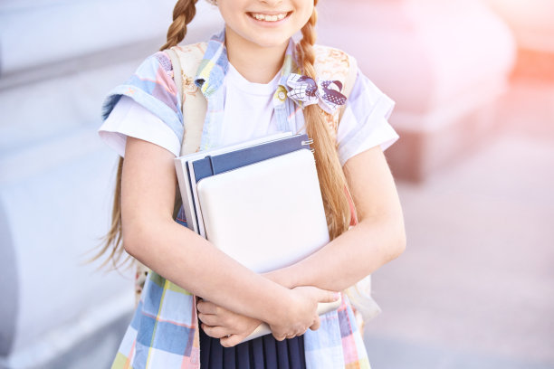 美丽的美国女学生肖像。学龄前儿童拿着书。微笑图片下载