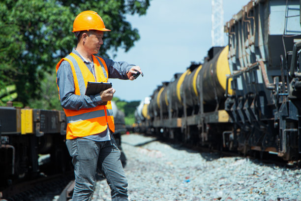 亚洲检查员工程戴头盔和背心工人制服检查铁路建设工作在轨道上。图片下载