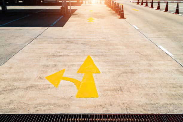 水泥路上的黄色箭头标志着停车场的入口。箭头在路上，黄色的照片。在一个室外停车场的路上。路上黄色箭头的照片。图片下载
