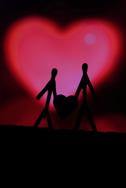 爱侣拿着火柴棍的概念。男性和女性靠得很近，背景是美丽的心形。火柴棒艺术摄影使用火柴棒创造人物。图片下载