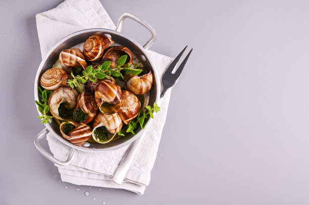 灰色的桌子上，在煎锅里煮着美味的海蜗牛图片下载