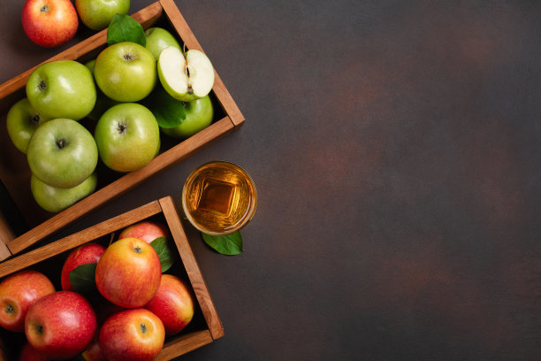成熟的红和绿苹果在木盒子与新鲜果汁在生锈的背景图片下载