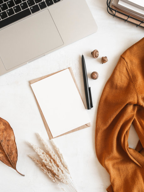 有笔记本电脑，储物篮，棕色毛衣，落叶和橡子，信封和明信片的家庭办公桌图片下载