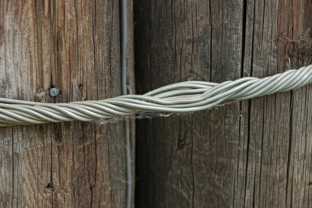灰色扭曲的金属丝将两根棕色的木柱子拉在一起图片下载