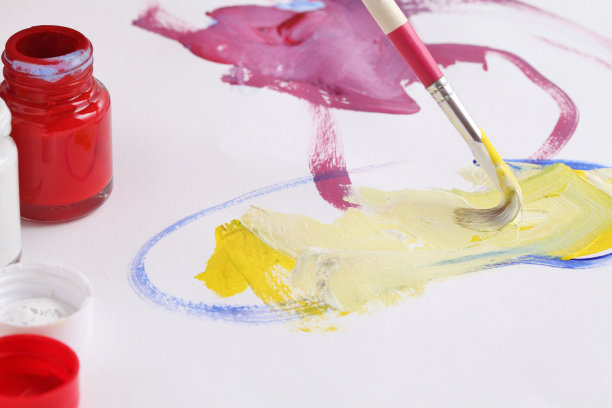 一个亚洲男孩用画笔和水彩画在白纸上图片下载