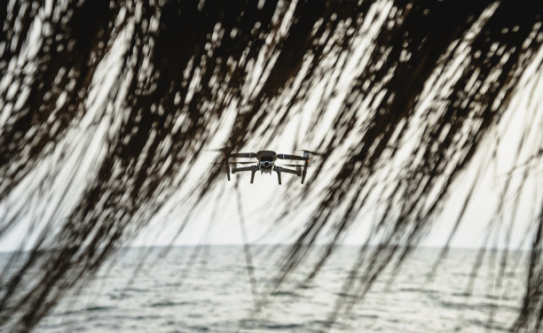 无人机与高分辨率数码相机飞行航拍海滩上壮观的日落天空-无人机飞在海滩上的人的安全-间谍和环境控制的概念图片下载