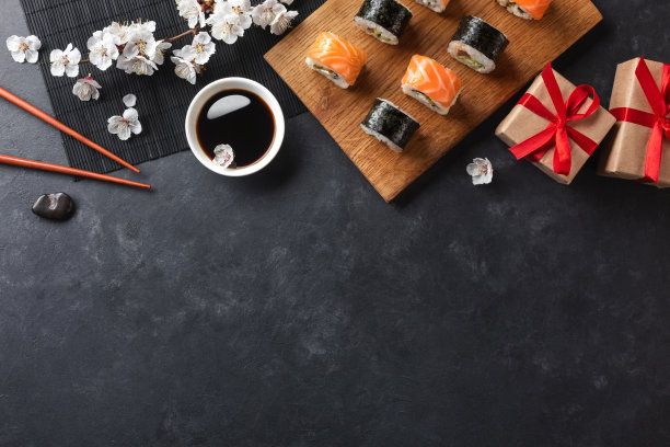 一套寿司，maki卷，礼盒与树枝的白花在石头桌上图片下载
