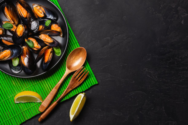 海鲜贻贝和罗勒叶装在竹席和石桌上的黑色盘子里图片下载