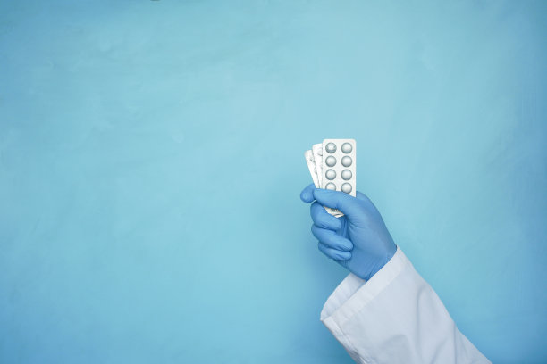 医生手拿吸塑包装对蓝色背景图片下载