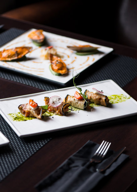 餐馆里的白盘子里放着茄子卷、奶酪、西红柿和罗勒图片下载