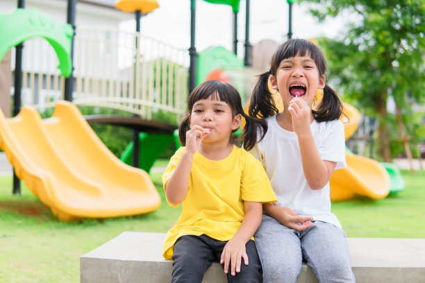 两个孩子在操场上玩，吃棒棒糖图片下载