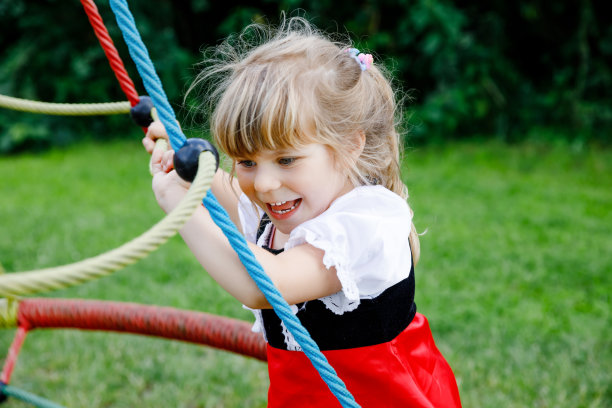 幼稚园小女孩在户外操场上玩耍。快乐的幼儿攀爬和有乐趣的夏季户外活动。图片下载