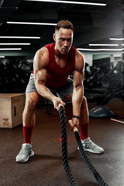 运动。壮汉在健身房用格斗绳练习。运动员在健身房练习格斗绳。戏剧性的运动背景图片下载