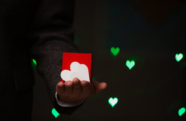 男人手持盒子和纸做的心图片下载